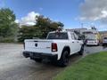 A white 2021 RAM 1500 pickup truck with a black bed liner and wheels parked on a paved surface