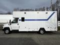 A white 2006 GMC C5000 with a boxy shape and blue stripes along the side, featuring a high roof and multiple compartments on the exterior