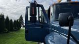 A blue 2009 International 4300 truck with an open door and side mirror visible