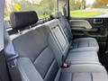 Backseat area of a 2017 GMC Sierra 1500 featuring grey fabric upholstery and seat belts in a clean and spacious configuration