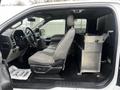 Interior view of a 2017 Ford F-150 showing the driver's seat steering wheel and a storage compartment beside the passenger seat