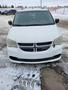 A white 2012 Dodge Grand Caravan facing forward with a distinctive front grille and headlights