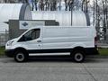 A white 2018 Ford Transit van viewed from the side with no visible cargo in the back and black accents on the lower body