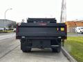 A 2021 Ford F-550 truck in black with a flatbed design parked on the road facing away from the viewer