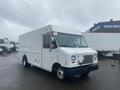 A white 2012 Ford Econoline truck with a boxy shape and large front windows parked in a lot with a blank grille and no visible logos