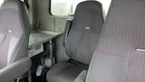 Interior seats of a 2012 International 7400 featuring gray upholstery and a metal table on one side