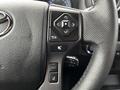 A close-up view of a steering wheel control panel featuring various buttons and a directional pad on a 2022 Toyota Tacoma