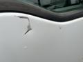 A close-up of a white 2010 Ford F-150 with noticeable paint scratches and scuffs on the truck body