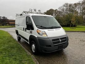 A white 2018 RAM Promaster van with a black front bumper and roof-mounted equipment, parked on a wet surface