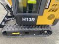A 2024 AGT Industrial H13R Mini Excavator showing its nameplate with H13R and a black rubber track with an arrow indicating motion direction