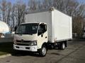 A 2015 Hino 195 box truck with a white cargo area and beige front cab parked on a street