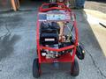 A red 2024 Magnum 4000 Hot Water Pressure Washer featuring a mounted engine and various controls displayed on the top panel with wheels for mobility