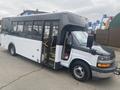 A 2018 Chevrolet Express shuttle bus in black and white with multiple windows and an open door revealing the interior seating area