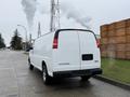 A white 2014 GMC Savana van parked on a street showing its rear view features a smooth body and large cargo space