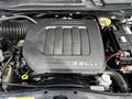 The image shows the engine compartment of a 2011 Dodge Grand Caravan featuring a 3.6L V6 engine cover with ridges and various components visible including a battery and hoses