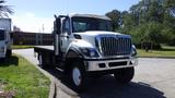 A white 2015 International 7400 truck with a flatbed and prominent grille showcasing round headlights and an extended cab