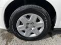 A close-up of a silver alloy wheel with five spokes mounted on a black tire with tread visible