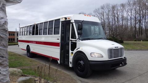 A 2013 Freightliner M2 106 school bus with a white body and red stripes parked with its door open