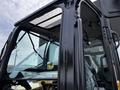 A 2024 Caterpillar 306 excavator showing its cab with large windows and control panel details visible inside