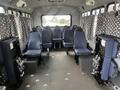 Interior of a 2012 Chevrolet Express with eight blue upholstered seats arranged in a row and four additional seats folded against the wall