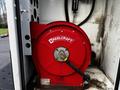 A red Q Reelcraft hose reel with a black hose coiled inside, mounted on a white vehicle interior