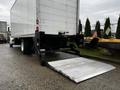 A 2018 Freightliner M2 106 box truck with a rear liftgate partially extended on a paved surface