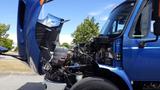 A blue 2012 International DuraStar 4300 truck with its hood raised revealing the engine and interior components