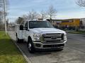 A white 2016 Ford F-350 SD with a flatbed design parked on the side of the road