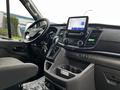 Interior view of a 2021 Ford Transit showcasing the dashboard with a touchscreen display and gear shifter along with the driver's seat and steering wheel