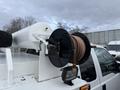 A close-up of a hose reel mounted on a vehicle featuring a white cylindrical tank and a coiled hose on a black spool