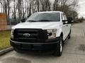 A white 2016 Ford F-150 truck is parked with its front angled towards the viewer showcasing its black grille and headlights