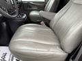A gray leather driver's seat in a 2014 GMC Savana with a seatbelt and a cup holder in the foreground