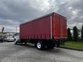 2008 Ford F-750 truck with a large red cargo box and a white cab parked on a gravel surface