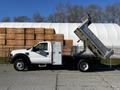 A 2008 Ford F-450 SD dump truck with a white exterior and a silver dump bed raised in the air