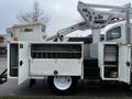 A 2013 International DuraStar bucket truck with an Altec aerial lift attachment and several open storage compartments on the side