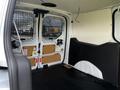 Interior view of a 2016 Ford Transit Connect cargo van showing a spacious rear area with metal grille separating the front cabin from the cargo space and minimal furnishings