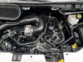 Engine compartment of a 2023 Ford Transit showcasing various components including pipes wires and the engine itself