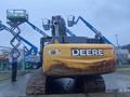 A yellow 2014 John Deere 350G excavator with a large bucket and heavy tracks positioned on a muddy surface