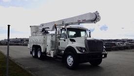 A white 2008 International 7500 bucket truck with a raised aerial lift and multiple compartments on the side for tools and equipment