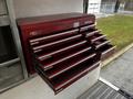 A 2006 GMC C5000 with a red tool chest featuring multiple drawers open and closed for tool storage