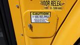 Close-up of a yellow diesel bus door with a caution sign indicating use of DEF only and a keyhole for access to the fuel compartment