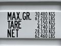 A 40 foot storage container with a roll-up door displaying weight specifications including maximum gross tare and net weights in kilograms and pounds