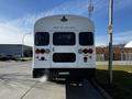 A 2022 Blue Bird Vision school bus with a white rear featuring red and amber lights and the label for the emergency door
