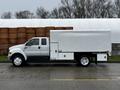 A 2013 Ford F-650 with a white cargo box, featuring a double cab and large wheels, parked on a pavement.