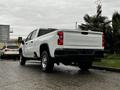 A 2021 Chevrolet Silverado 3500HD pickup truck in white with a visible bed and rear taillights, parked on a street