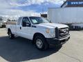 A 2013 Ford F-250 Super Duty pickup truck in white with a black front grille and single cab design is parked diagonally in the foreground