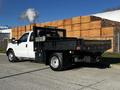 A 2011 Ford F-350 SD truck with a flatbed and tool storage in the back smoke rising from the exhaust