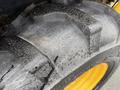 Close-up of a rugged tire from a 2011 John Deere 310SJ 4x4 Wheel Loader showing tread pattern and wear