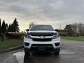 A 2019 Chevrolet Colorado facing the viewer with a white exterior and a black hood