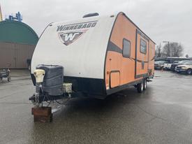 A 2015 Winnebago Of Indiana Travel Trailer with an orange and silver exterior featuring the Winnebago logo on the front and a hitch at the bottom front